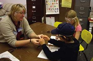 student helping kids make wire ants